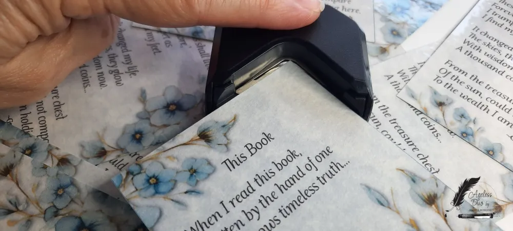 Handcrafted blue parchment bookmark featuring forget-me-not flowers and an original poem by Gregory Rongish, laminated with an eyelet and tassel while the corners are being rounded