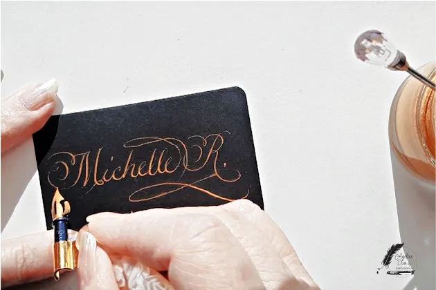 Live Event Calligraphy in Gold Metallic Ink Live event calligraphy by Jeanita of Ageless Duo, writing Copperplate script in gold metallic ink on a black place card